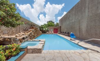 a backyard with a pool surrounded by lounge chairs and a hot tub , creating a relaxing atmosphere at Hotel Ava Laredo