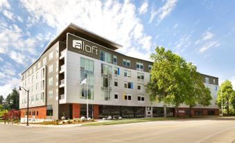"a large building with a white exterior and the words "" loft "" written on it is surrounded by trees" at Aloft Hillsboro-Beaverton