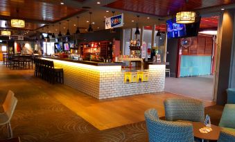 a well - lit restaurant with a bar area and various dining tables , creating an inviting atmosphere for customers at Wallacia Hotel