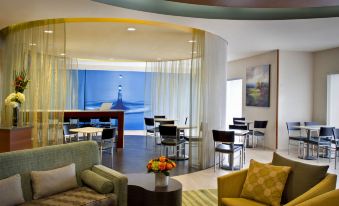 a modern hotel lobby with various seating options , including couches , chairs , and a dining table at SpringHill Suites Long Island Brookhaven