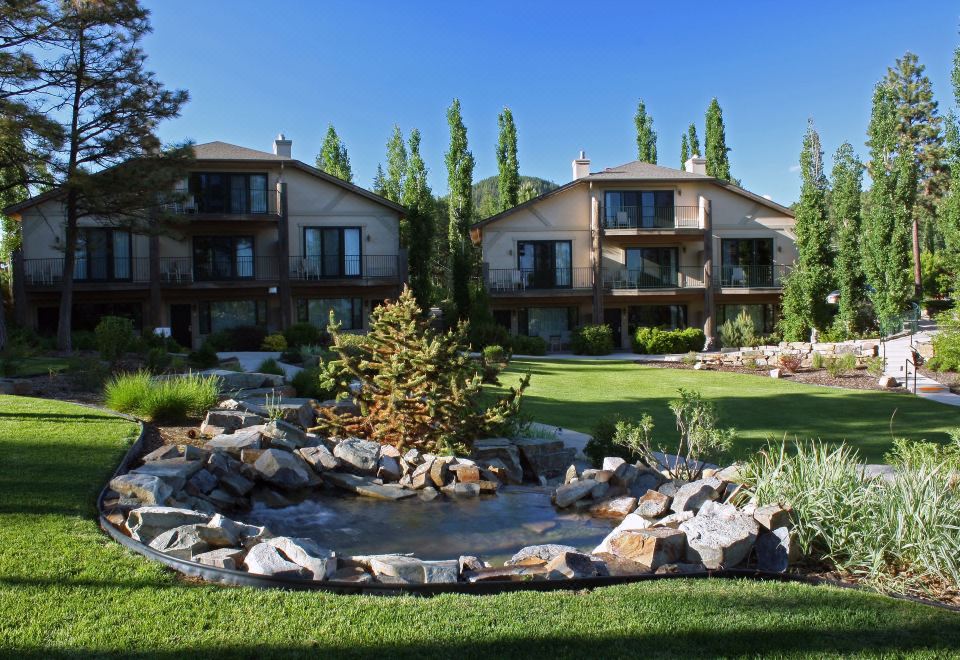 a picturesque residential area with multiple houses , surrounded by lush greenery and a pond filled with water lilies at Mountain Lake Lodge