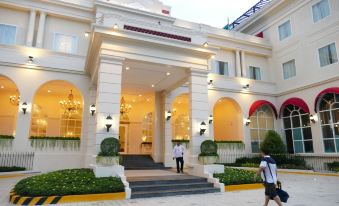 a group of people walking down the street in front of a white building with a red awning at Rizal Park Hotel