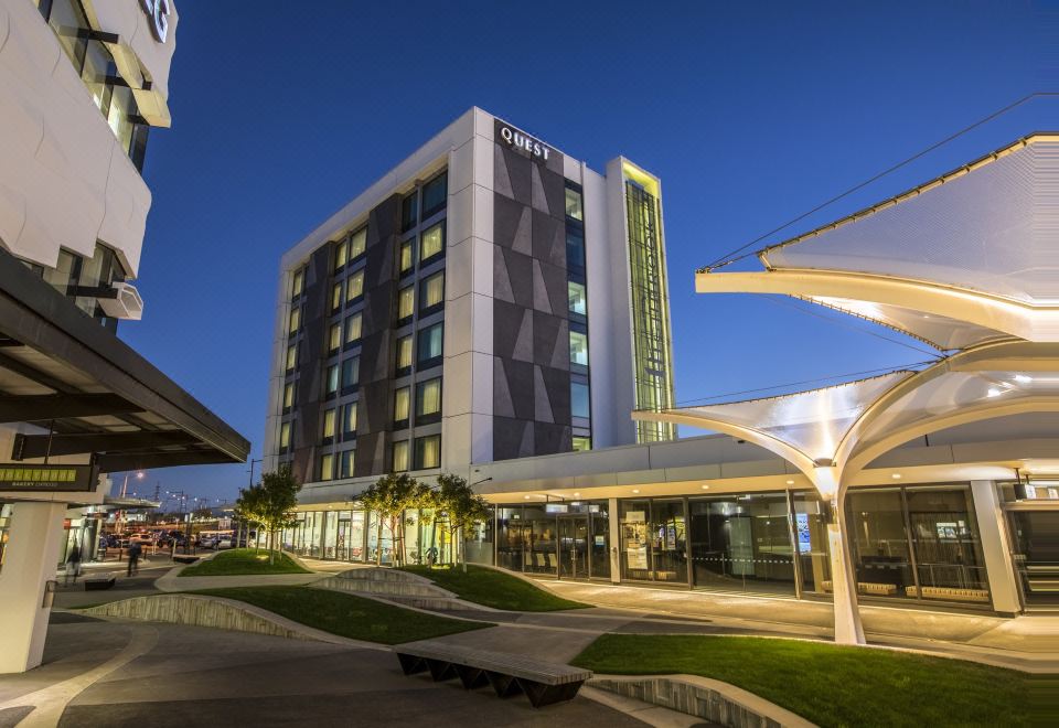 a modern hotel building with a large glass window , surrounded by trees and a parking lot at Quest Highbrook