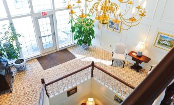 a grand staircase with a chandelier and potted plants , leading to an open doorway on the second floor at The Farmington Inn and Suites