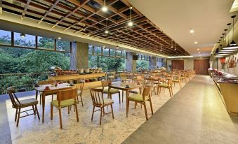 a large dining room with wooden tables and chairs arranged for a group of people at FamVida Hotel Lubuklinggau Powered by Archipelago