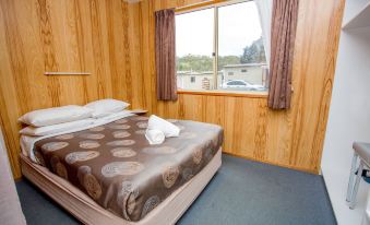 a bed with a brown and white patterned blanket is in a room with wooden walls at Discovery Parks - Hobart