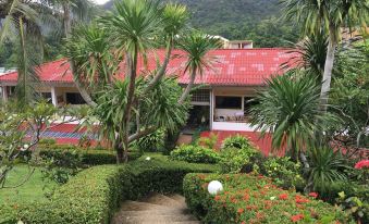 a red roof house surrounded by lush greenery , with stairs leading up to the entrance at Top Resort