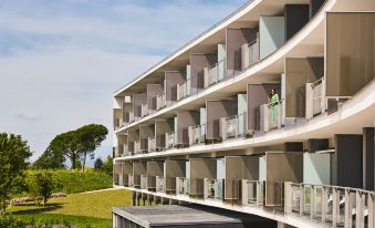 a modern apartment building with multiple balconies and a green lawn in the background at Camiral Golf & Wellness - Leading Hotel of the World