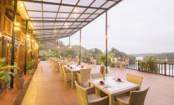 an outdoor dining area with a variety of tables and chairs , some of which are covered in white tablecloths at Phong Nha Lake House Resort