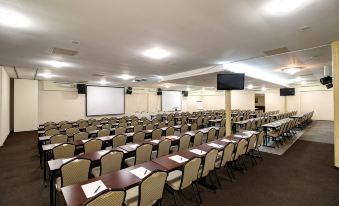 an empty conference room with rows of chairs and tables , a projector screen , and a screen at the end of the room at Hotel Dixon so Vstupom do bazéna a vírivky Zdarma - Free Entrance to Pool and Jacuzzi Included