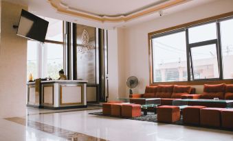 a modern living room with a large window , orange couch , and coffee table , along with a fan and a television at Amanda Hotel