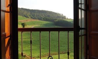 a view of a green field through an open window with a black iron fence at El Castro