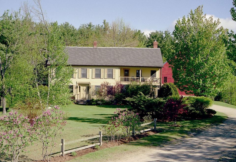 a yellow house surrounded by trees and grass , with a garden in front of it at The Waterford Inne