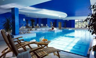 a large indoor swimming pool surrounded by lounge chairs , with people enjoying their time in the water at Actons Hotel Kinsale