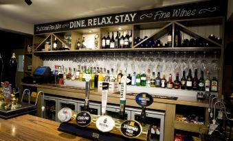 a bar with a variety of bottles and glasses , as well as a variety of beer taps at Burlton Inn