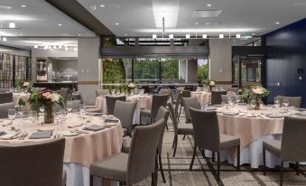 a well - decorated dining room with tables covered in white tablecloths and chairs arranged for a formal event at Rydges Campbelltown an EVT hotel