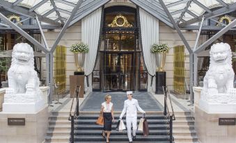 a man and a woman are walking up the stairs of a grand hotel , carrying shopping bags at The Peninsula Paris