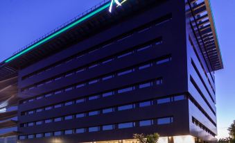 "a modern building with the word "" radisson "" on top , lit up at night , and parked cars in front" at Radisson Hotel Santa Cruz