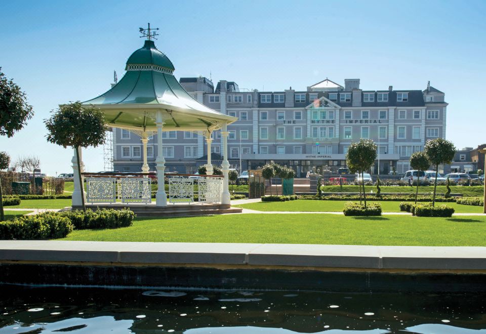 a large building with a green roof is surrounded by a pond and a gazebo at Cbh Hythe Imperial Hotel Golf and Spa