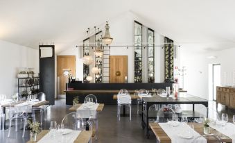 a modern restaurant with white walls , wooden tables , and chairs , as well as a bar area at Torre de Palma Wine Hotel, Montforte, a Member of Design Hotels