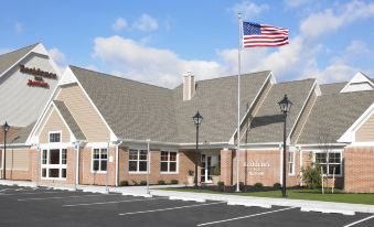 a brick building with an american flag flying in front of it , surrounded by trees and grass at Residence Inn Harrisburg Carlisle