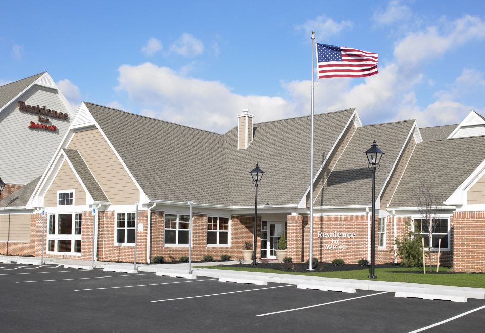 a brick building with an american flag flying in front of it , surrounded by a parking lot at Residence Inn Harrisburg Carlisle