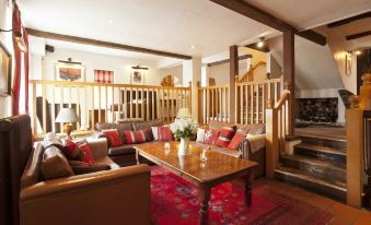 a spacious living room with a large wooden table , brown leather couches , and a red rug at The Newbridge on Usk