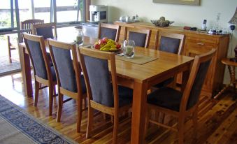 a dining room with a wooden dining table surrounded by chairs , and a refrigerator in the background at Sea Dragon Kangaroo Island