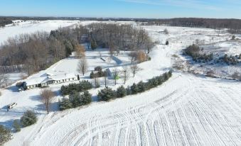 aerial view of a snow - covered field with trees and a body of water in the background at White House Farm