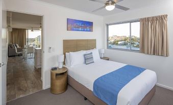 a clean and well - organized hotel room with a comfortable bed , a ceiling fan , and a window overlooking the ocean at Direct Collective - Pavilion and Governor on Brookes