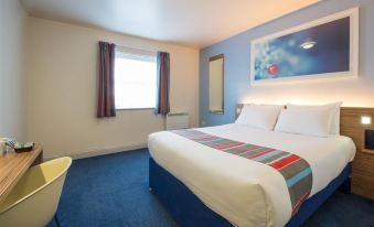 a clean and well - organized hotel room with a large bed , white bedding , and a blue carpet at Travelodge Wincanton