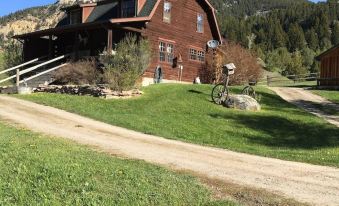 a large wooden house with a green lawn and a gravel driveway in front of it at Diamond J Ranch