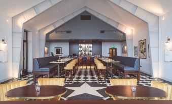 a modern restaurant with a black and white checkered floor , gold tables , and gold chairs at Titanic Hotel Belfast