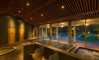 a large indoor pool surrounded by glass walls , with several people relaxing in the water at Alba Wellness Resort by Fusion