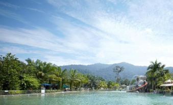 a large pool surrounded by palm trees , with a group of people enjoying their time at the resort at Felda Residence Hot Springs
