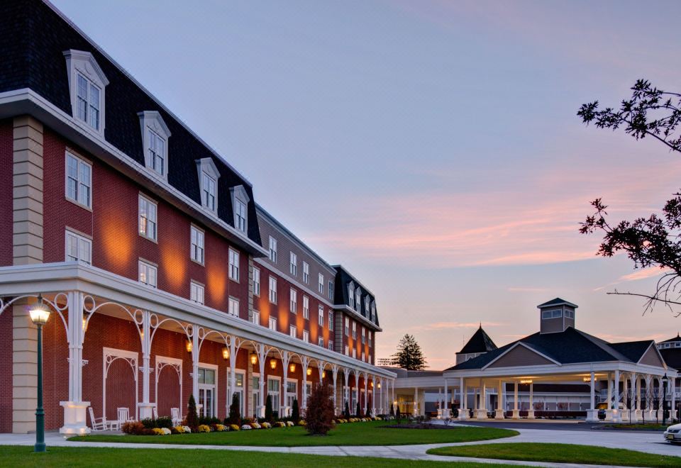 a large building with a red brick facade and white trim is surrounded by green grass and trees at Saratoga Casino Hotel