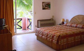 a well - decorated bedroom with a large bed , white tiled floor , and sliding glass door leading to a balcony at Coral Caribe