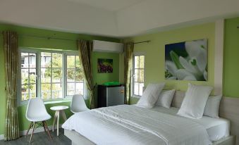 a large , well - made bed with white linens is in a room with green walls and a window at Bunny Hill Resort