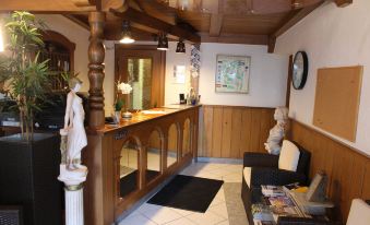 a hotel lobby with a wooden reception desk and a large painting on the wall at Hotel Restaurant Post Italia