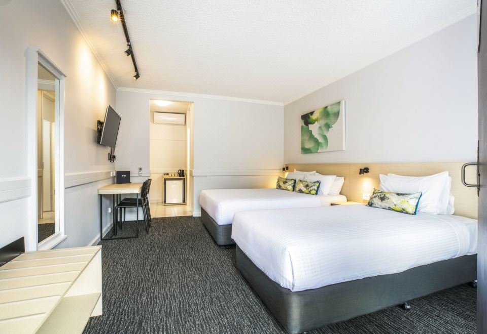 a modern hotel room with two beds , a desk , and a tv , all neatly arranged at Nightcap at Matthew Flinders Hotel