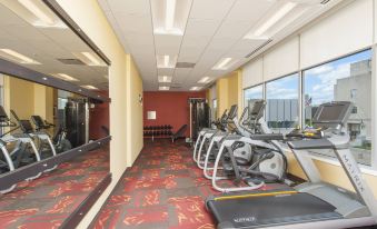 a gym with treadmills and exercise equipment , located next to a large window with blinds on the windows at Courtyard Peoria Downtown