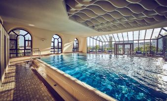 an indoor swimming pool with a glass ceiling , allowing natural light to fill the space at Hotel Nassauer Hof