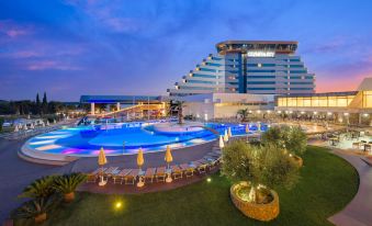 a large , modern hotel with a pool and outdoor seating area at dusk , illuminated by lights at Hotel Olympia