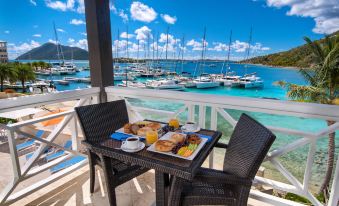 a dining table set with breakfast items on a balcony overlooking a marina filled with boats at Scrub Island Resort, Spa & Marina