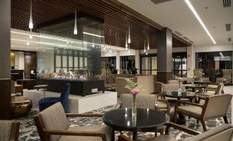 a modern hotel lobby with comfortable seating , large windows , and a bar area under a wooden ceiling at DoubleTree by Hilton Hotel Syracuse