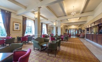 a large hotel lobby with multiple couches , chairs , and tables arranged for guests to relax and socialize at Cumbria Grand Hotel