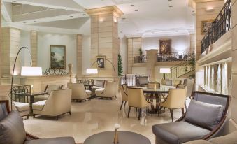 a luxurious hotel lobby with multiple seating areas , including couches , chairs , and a dining table at Amman Marriott Hotel