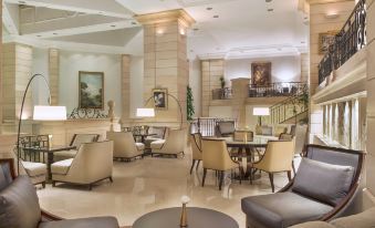 a modern , elegant living room with marble floors and beige walls , featuring multiple couches and chairs arranged around a dining table at Amman Marriott Hotel