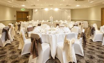 a well - decorated banquet hall with tables covered in white tablecloths and chairs arranged for a formal event at Holiday Inn Glasgow - East Kilbride