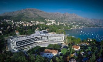a large hotel complex surrounded by mountains and water , with boats docked in the harbor at Sheraton Dubrovnik Riviera Hotel